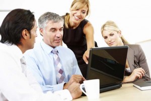 businesswoman showing colleagues something on laptop
